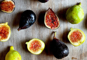 Whole and sliced figs on cutting board