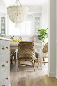 light filled kitchen with antique brass cabinet knobs, wood floors and natural woven chairs.