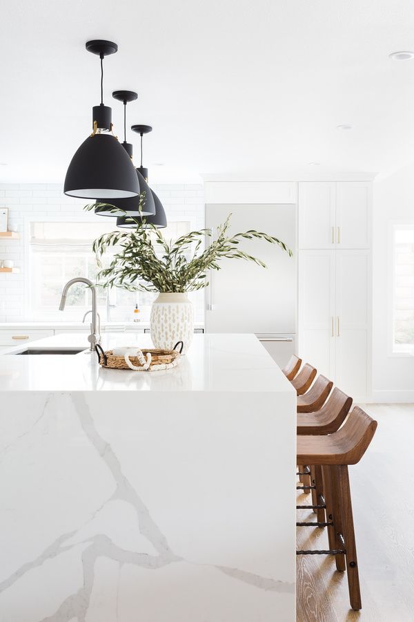 Kitchen with quartz 'waterfall' style island and black schoolhouse pendants.