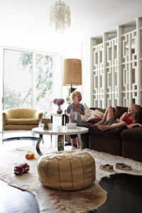 Light filled family room with children lounging on sofa next to a retro mid-century modern wall divider.