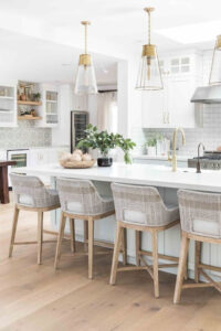 All white kitchen with island and antique brass and glass pendants.