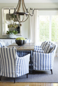 Blue and white striped slipcovered dining chairs around a natural finish table