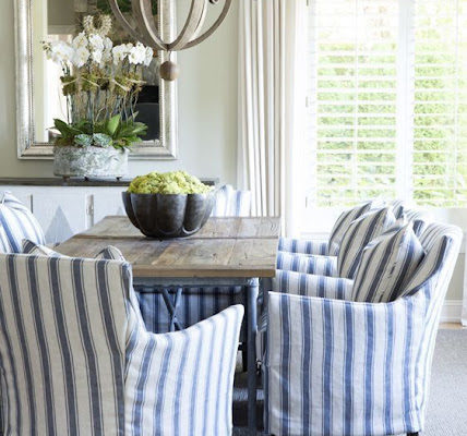 Blue and white striped slipcovered dining chairs around a natural finish table