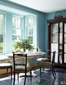 Banquette, table and chairs in a sunny room with beautiful blue walls. Via Architectural Digest.