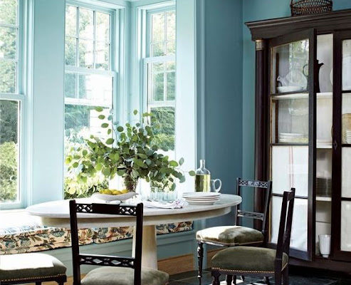 Banquette, table and chairs in a sunny room with beautiful blue walls. Via Architectural Digest.