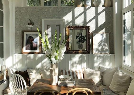 Light and shadow filled breakfast room decorated with an abundance of plants.