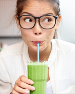 Woman sipping a green smoothie.